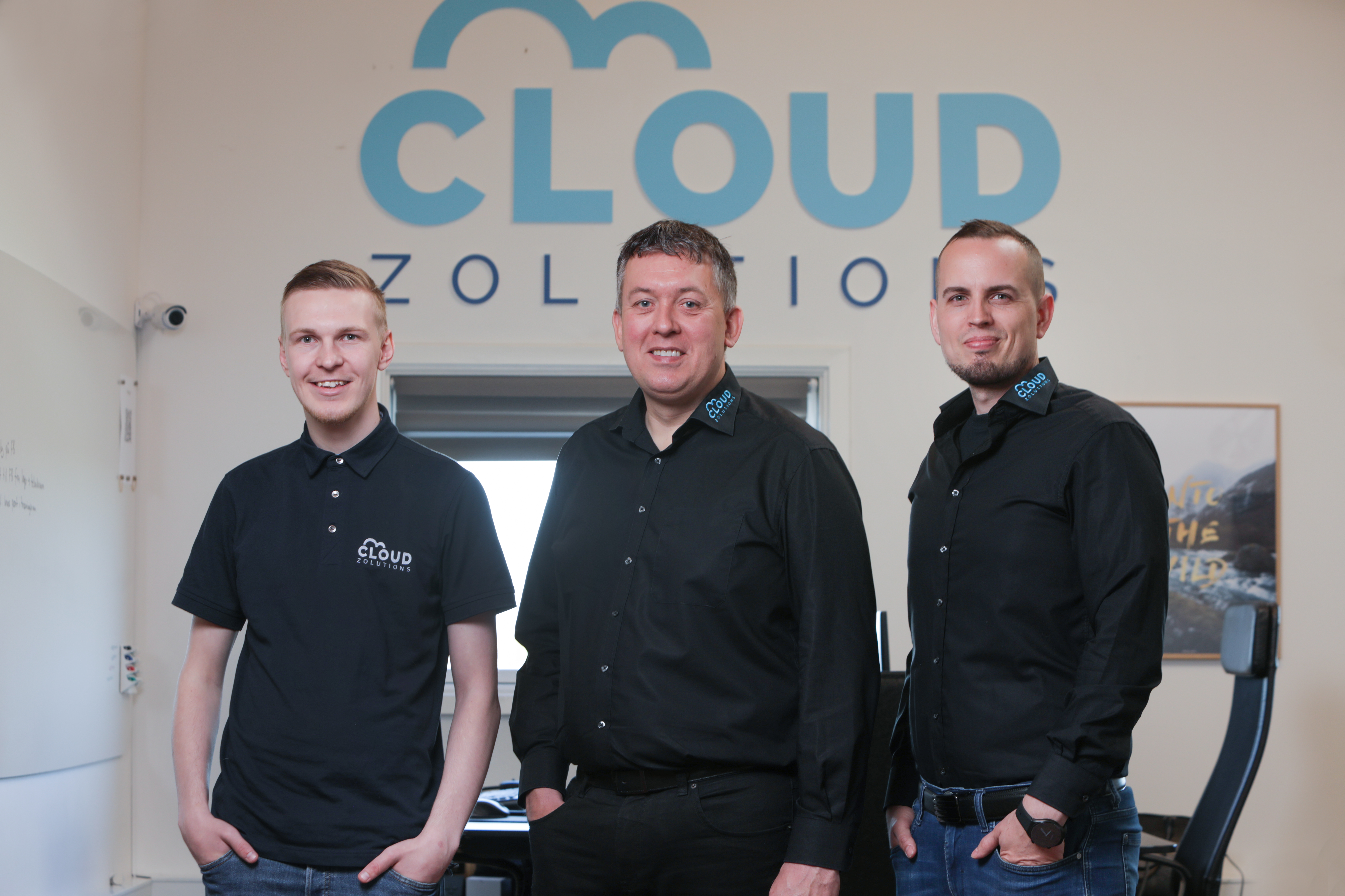 Cloud Zolutions teamet foran firmaets logo